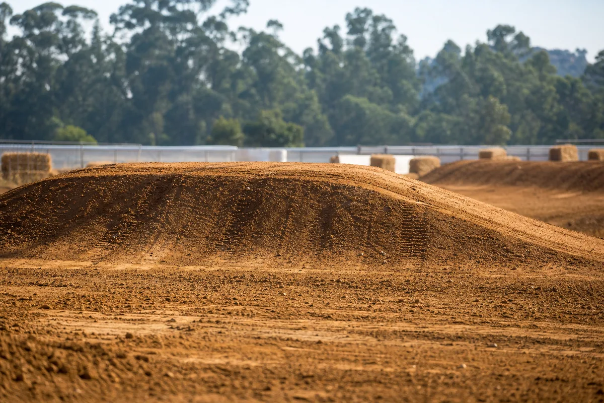 Vue latérale d’une table de motocross sur un circuit en terre, appel long et réception en pente